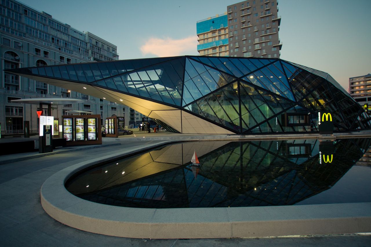 The angular glass McDonald's building in Batumi reflected in the pool in front of it at dusk