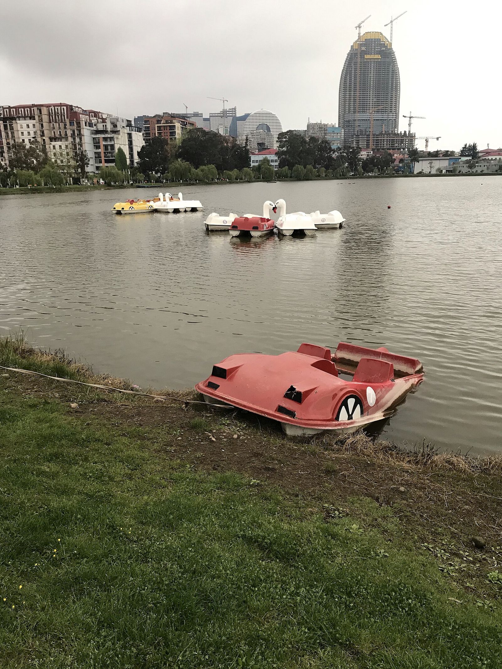 Pedalos on Lake Nurigeli in Batumi's May 6 Park, with one pulled up on the grassy bank