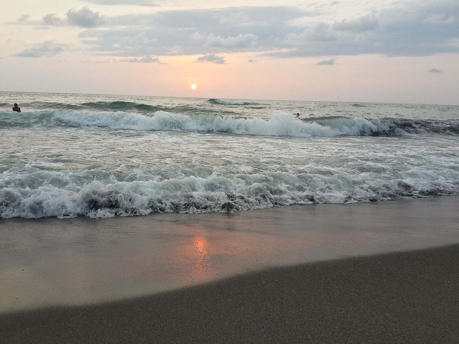 Waves breaking on the dark sand beach at Ureki at sunset