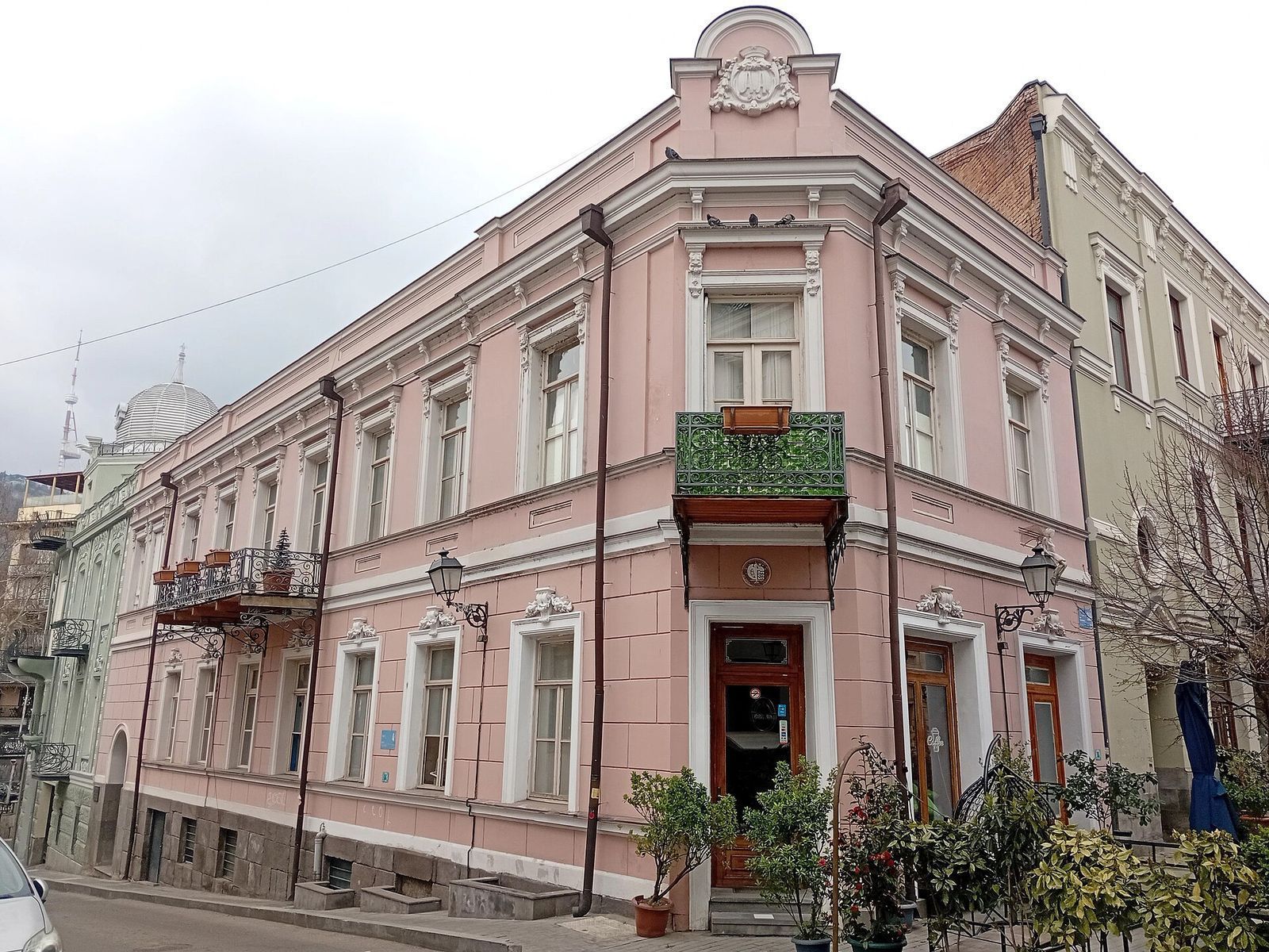 A restored pink 19th-century corner house with a green iron balcony on Aghmashenebeli Avenue in Chughureti