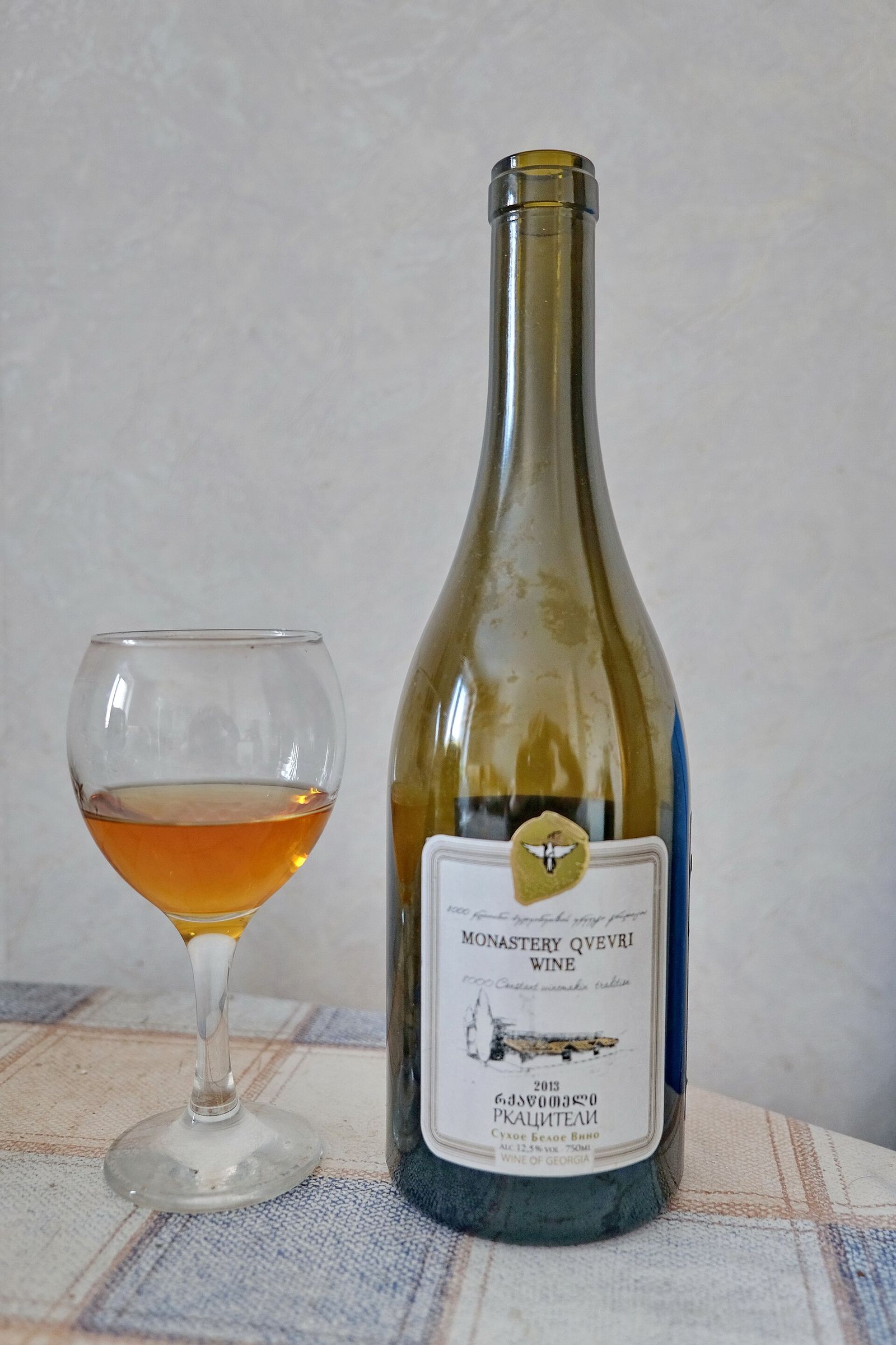 A glass of amber Rkatsiteli qvevri wine next to its bottle