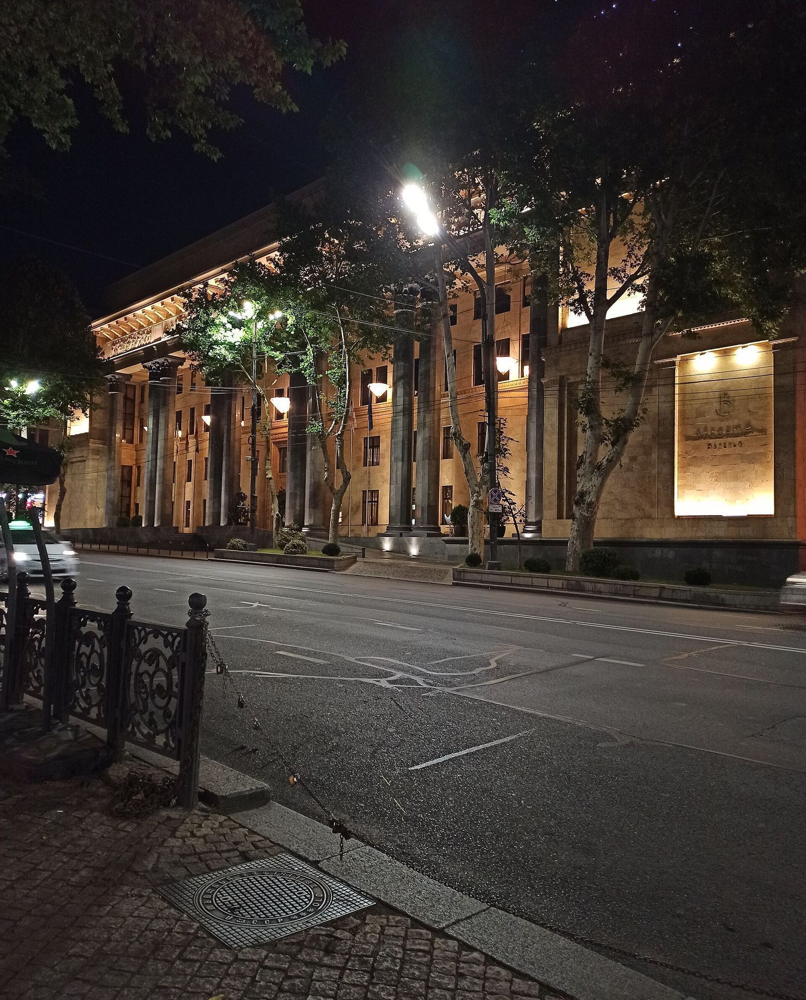 The colonnaded 1930s IMELI building on Rustaveli Avenue at night, the lit front of the Biltmore Tbilisi