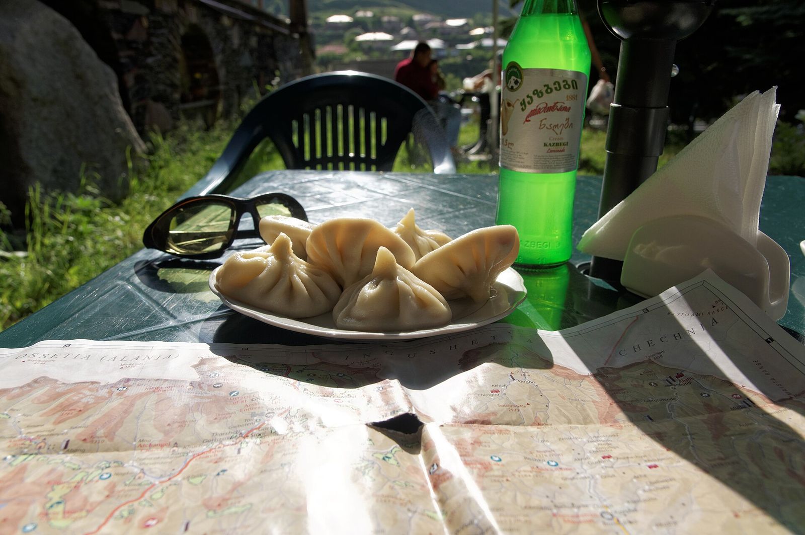 A plate of khinkali and a bottle of lemonade on an outdoor table in Kazbegi