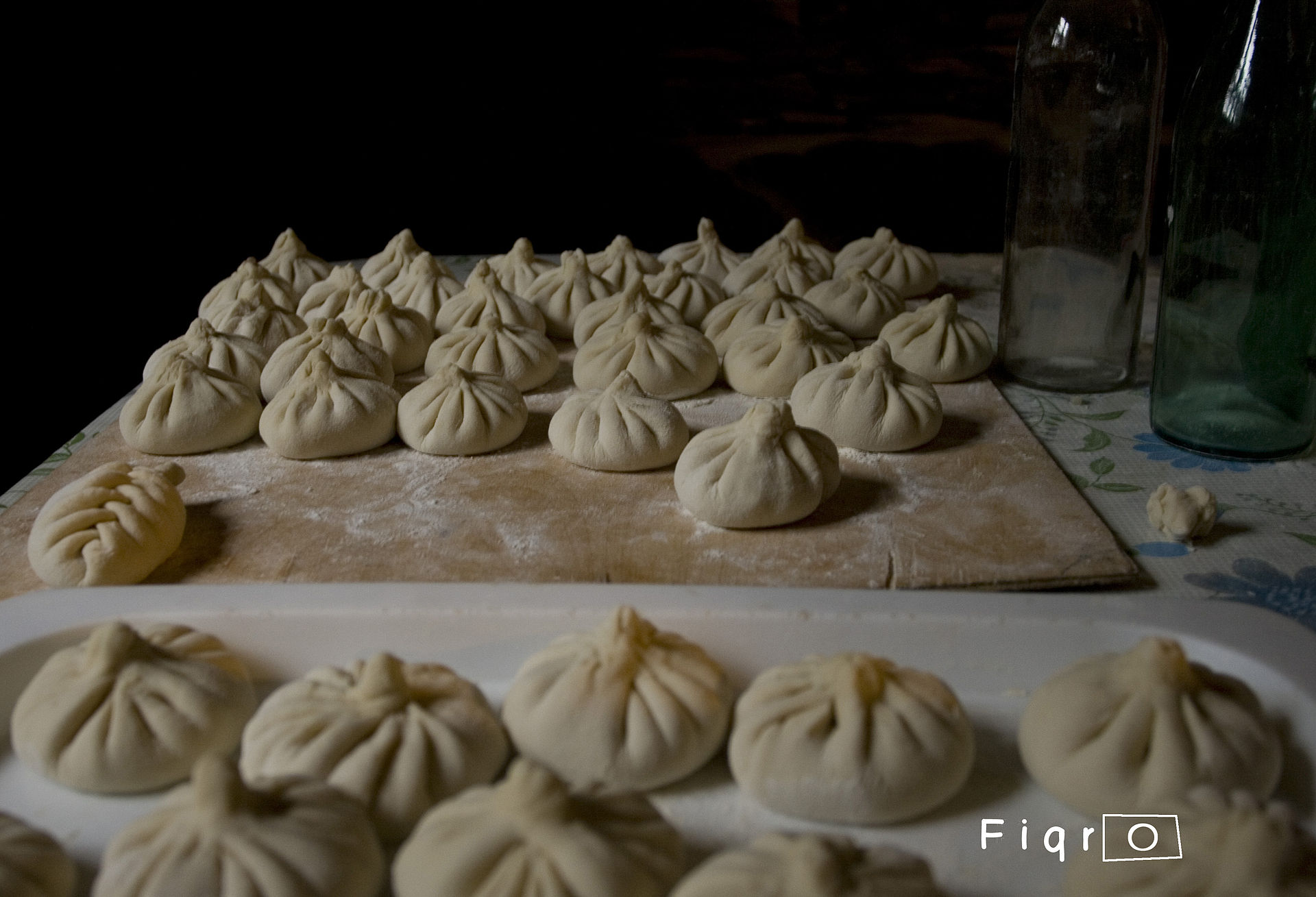 Rows of hand-pleated khinkali on a floured board, waiting to be boiled
