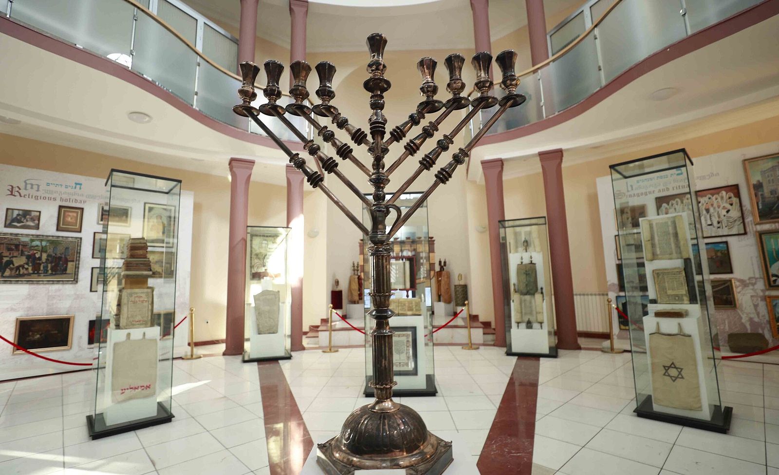 A large menorah and glass display cases in the main hall of the David Baazov Museum of History of Jews of Georgia in Tbilisi