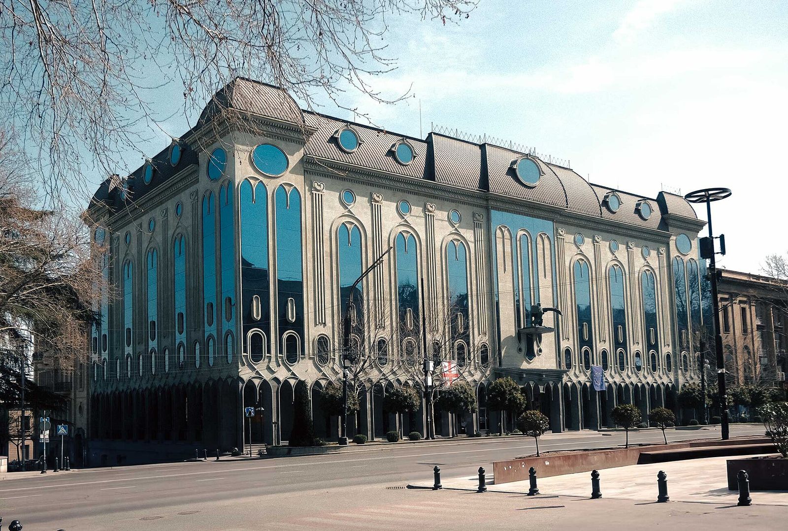 The Georgian Museum of Fine Arts on Rustaveli Avenue, a pale stone building with tall arched blue glass windows and oval windows in its roof