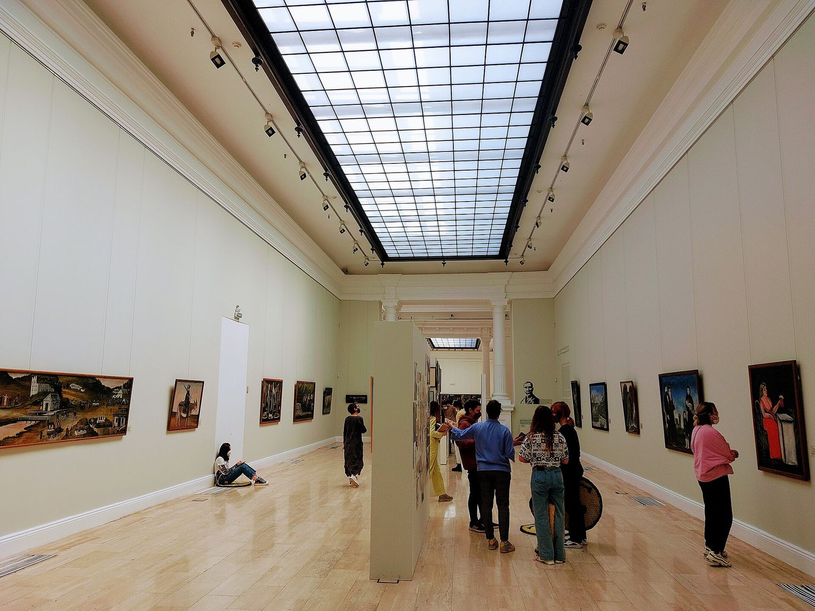Visitors in the skylit Pirosmani hall of the National Gallery on Rustaveli Avenue, with his paintings along both walls