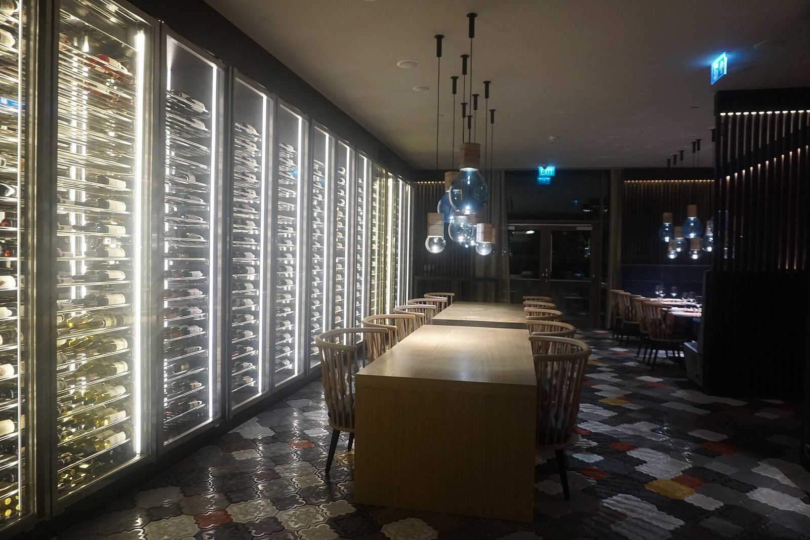 The glass-fronted wine wall and long table inside Ati, the rooftop restaurant and bar at the Sheraton Grand Tbilisi Metechi Palace