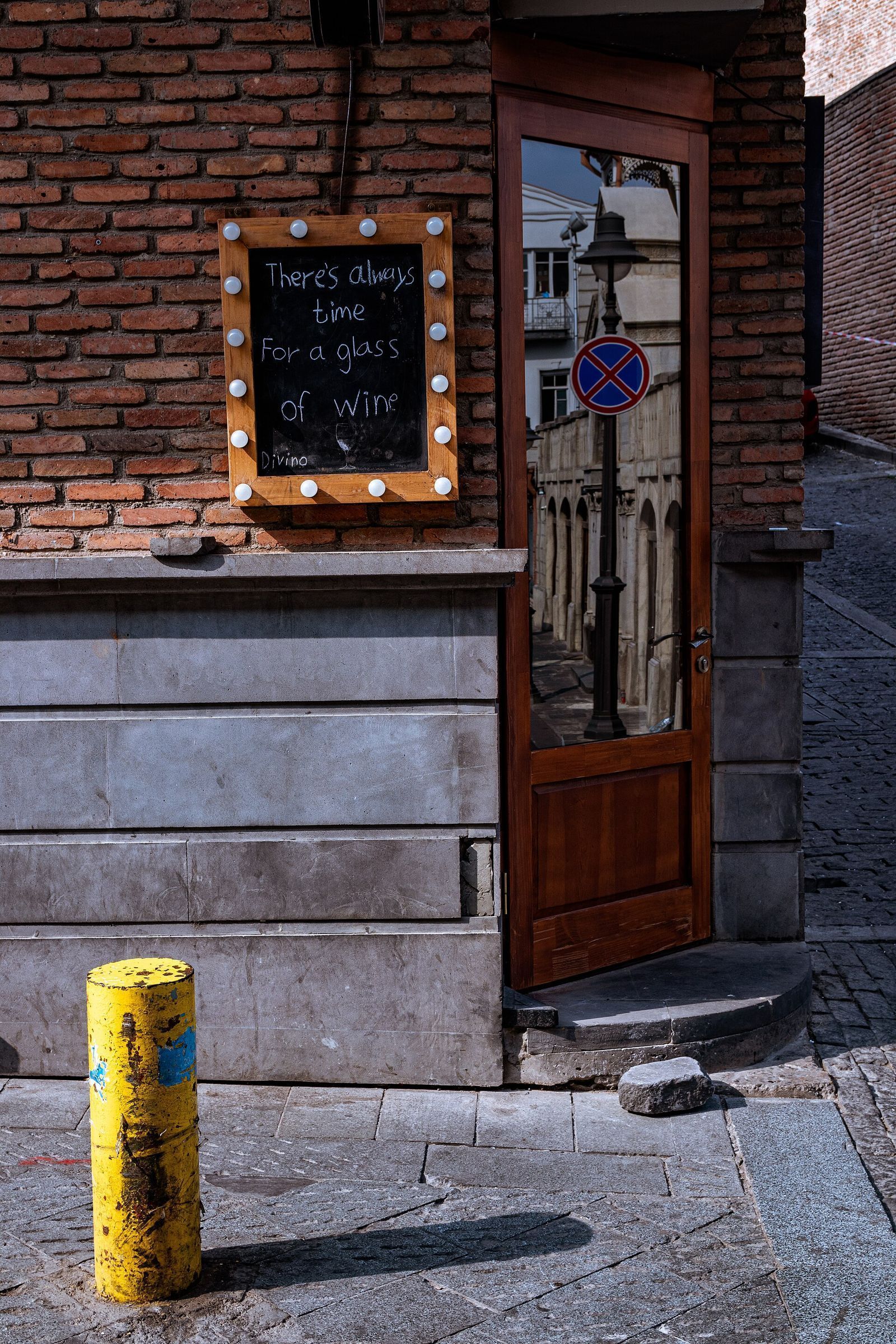 The doorway of a small wine bar on Samghebro Street in Tbilisi's Old Town, with a chalkboard sign about a glass of wine