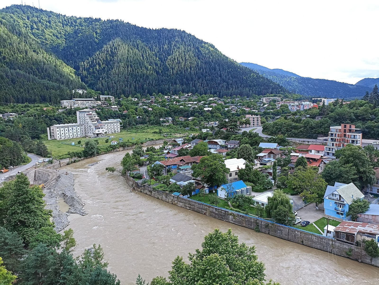 Borjomi town on the bend of the Mtkvari river, with forested mountains rising behind the houses and old sanatorium blocks