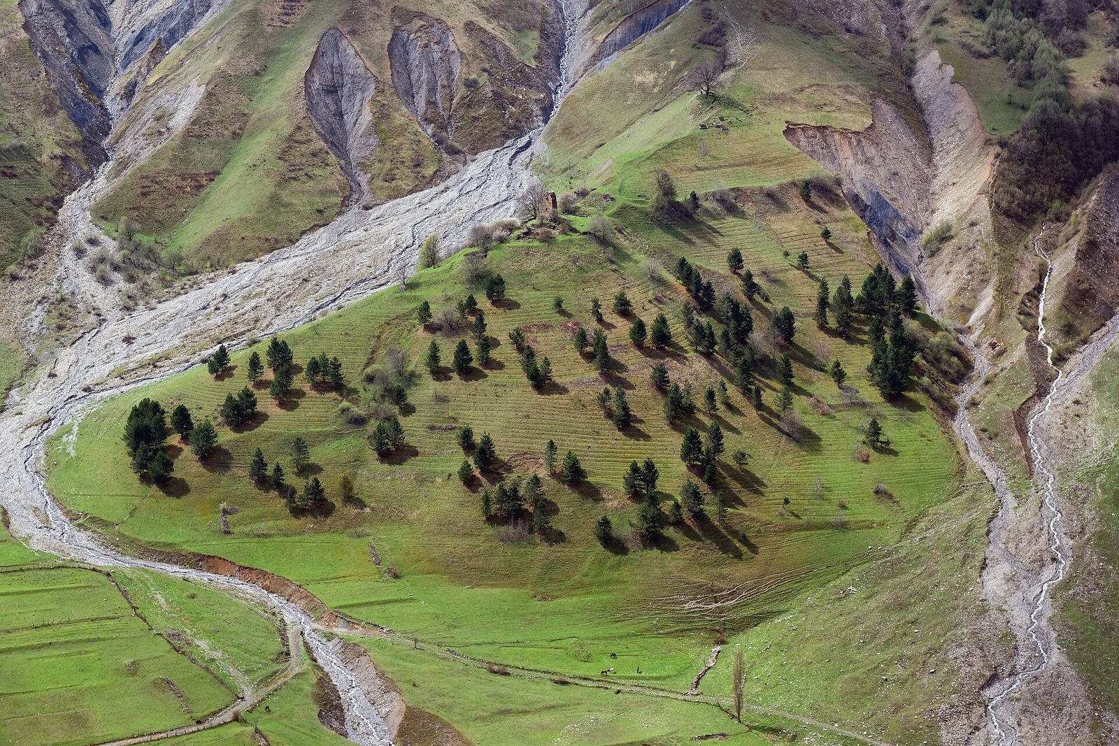 The Georgian Military Road winding along a green mountain valley below snow-streaked peaks
