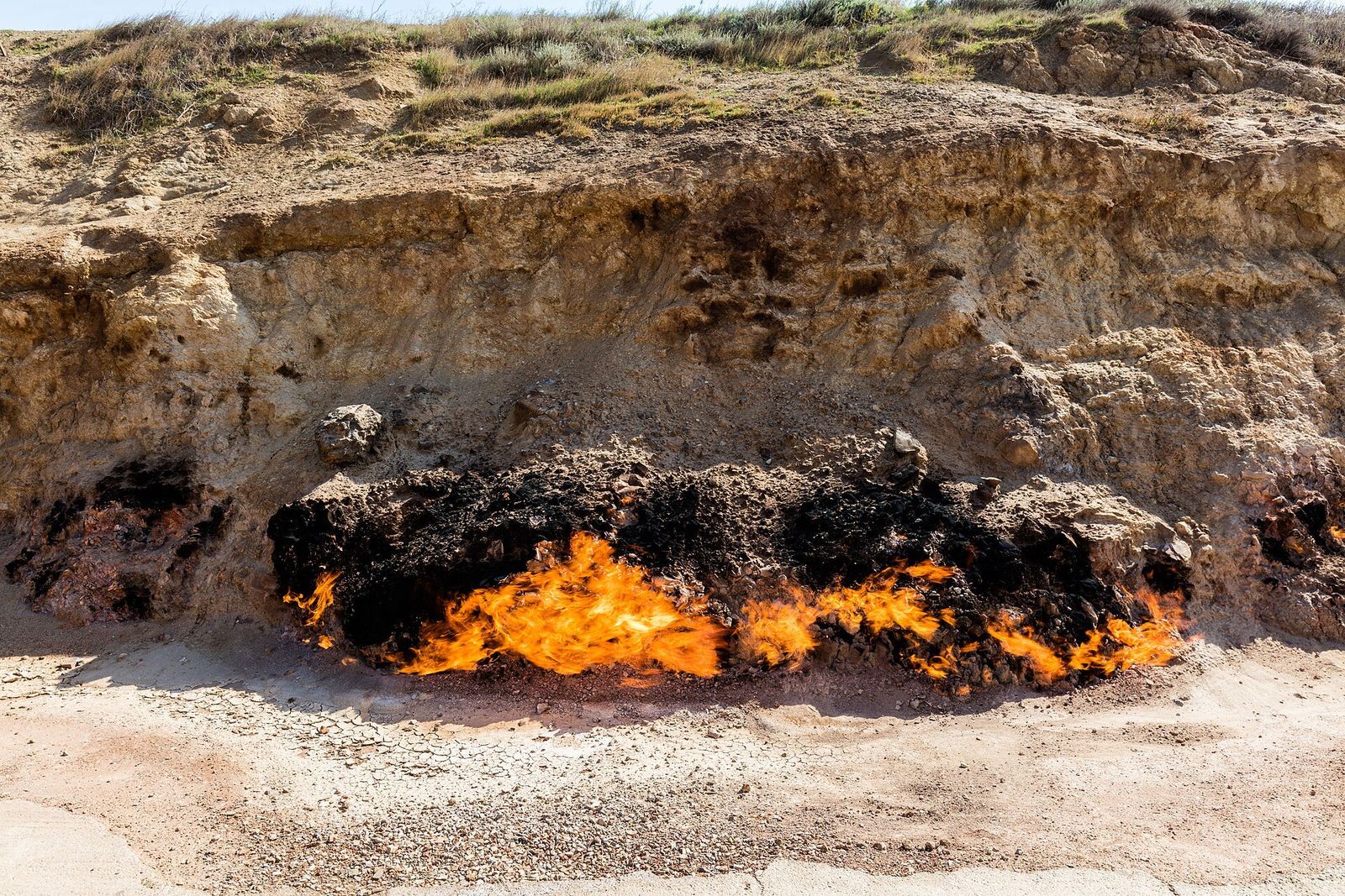 Flames burning along the foot of a sandstone bank at Yanar Dag on the Absheron peninsula, Azerbaijan