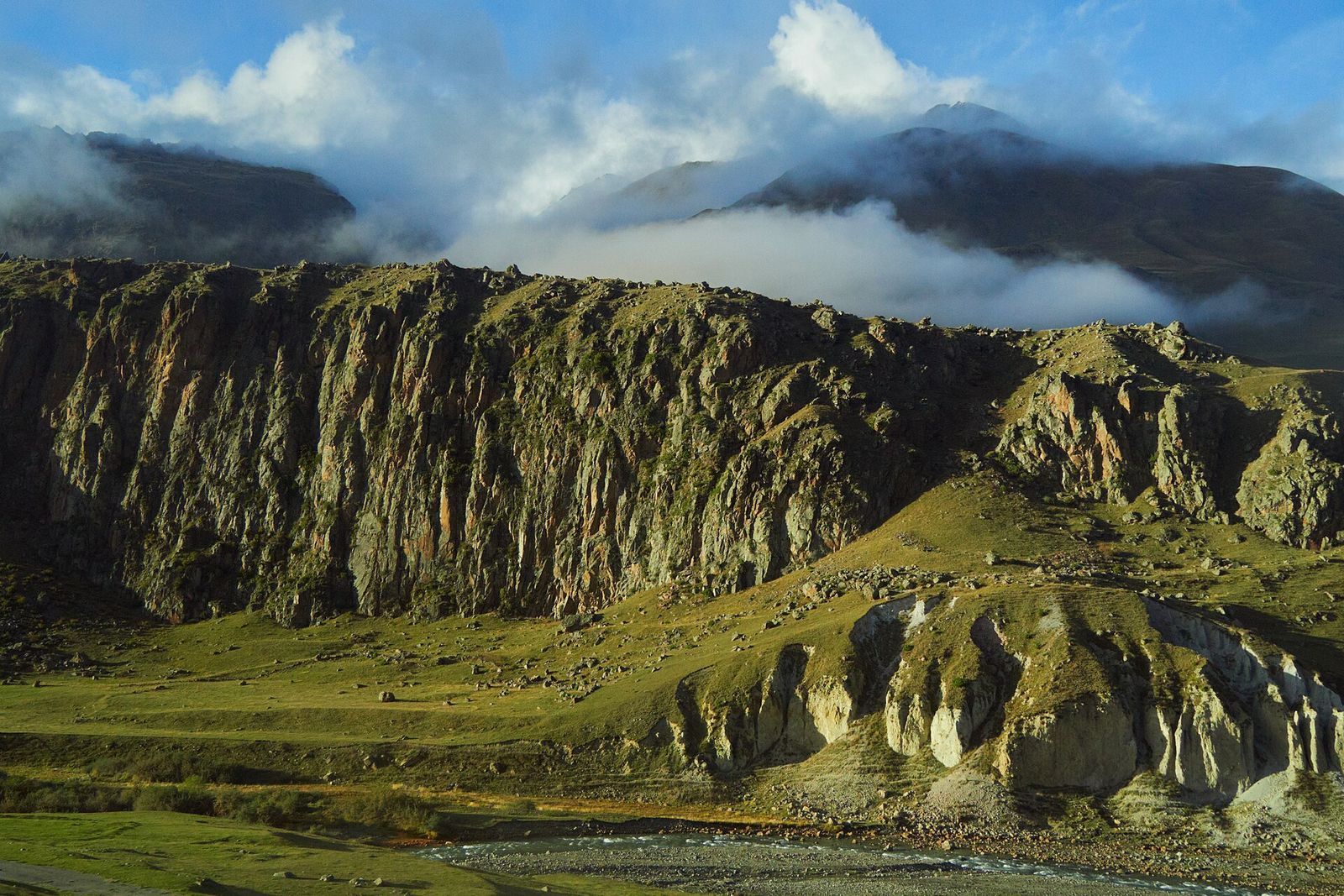 A rocky cliff face and river valley in the Caucasus Mountains.