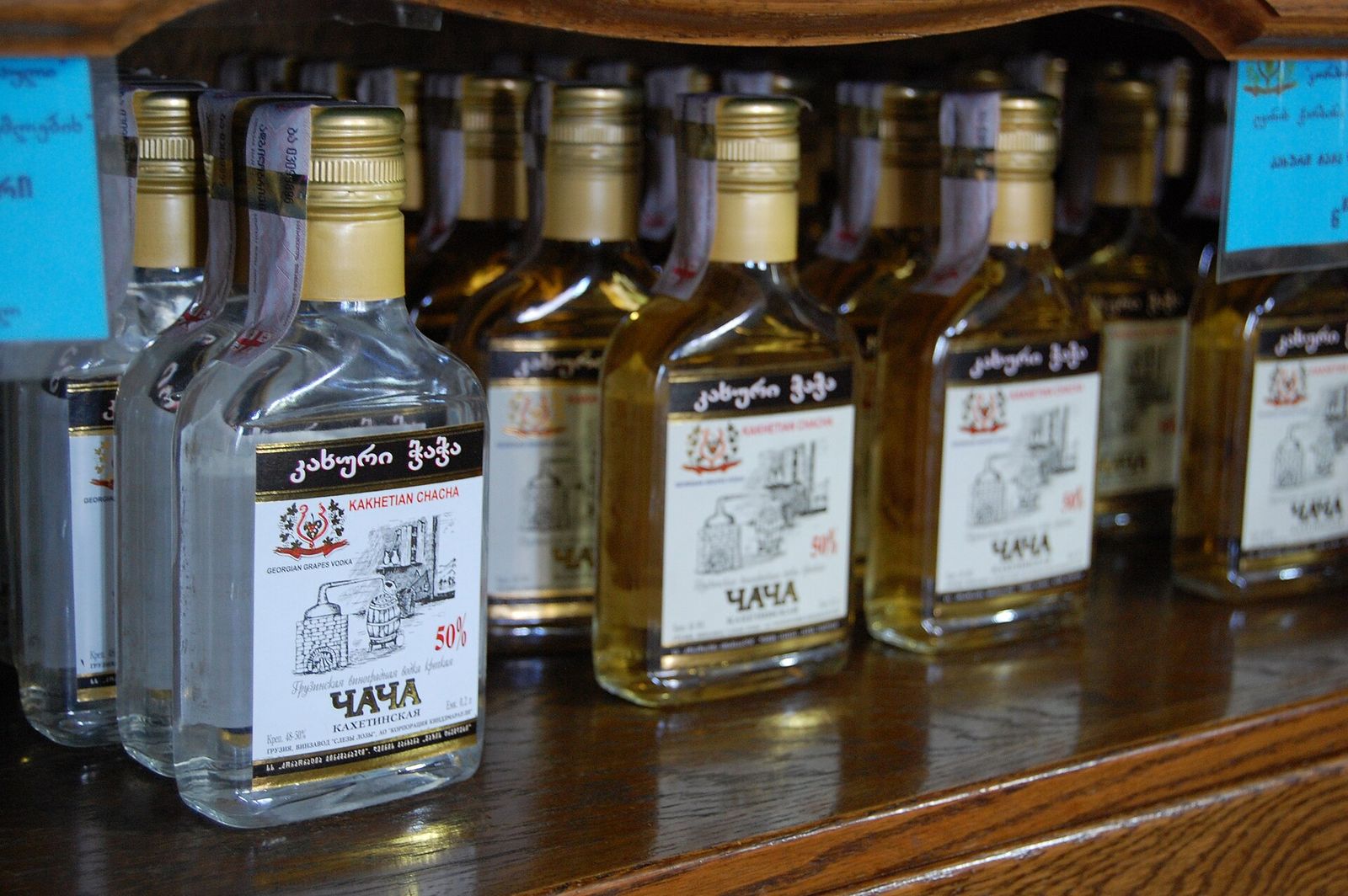 A bottle of clear white Kakhetian chacha at the front of a shelf of chacha bottles