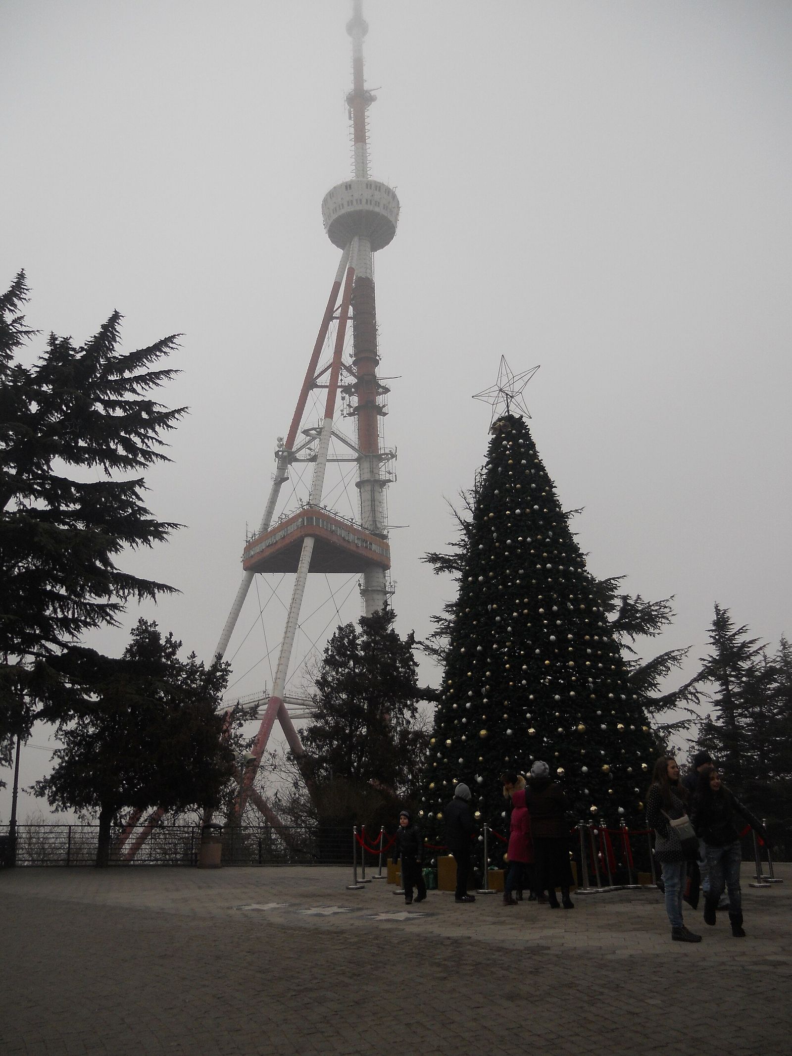 A decorated New Year tree beside the TV tower in Mtatsminda Park on a foggy January day
