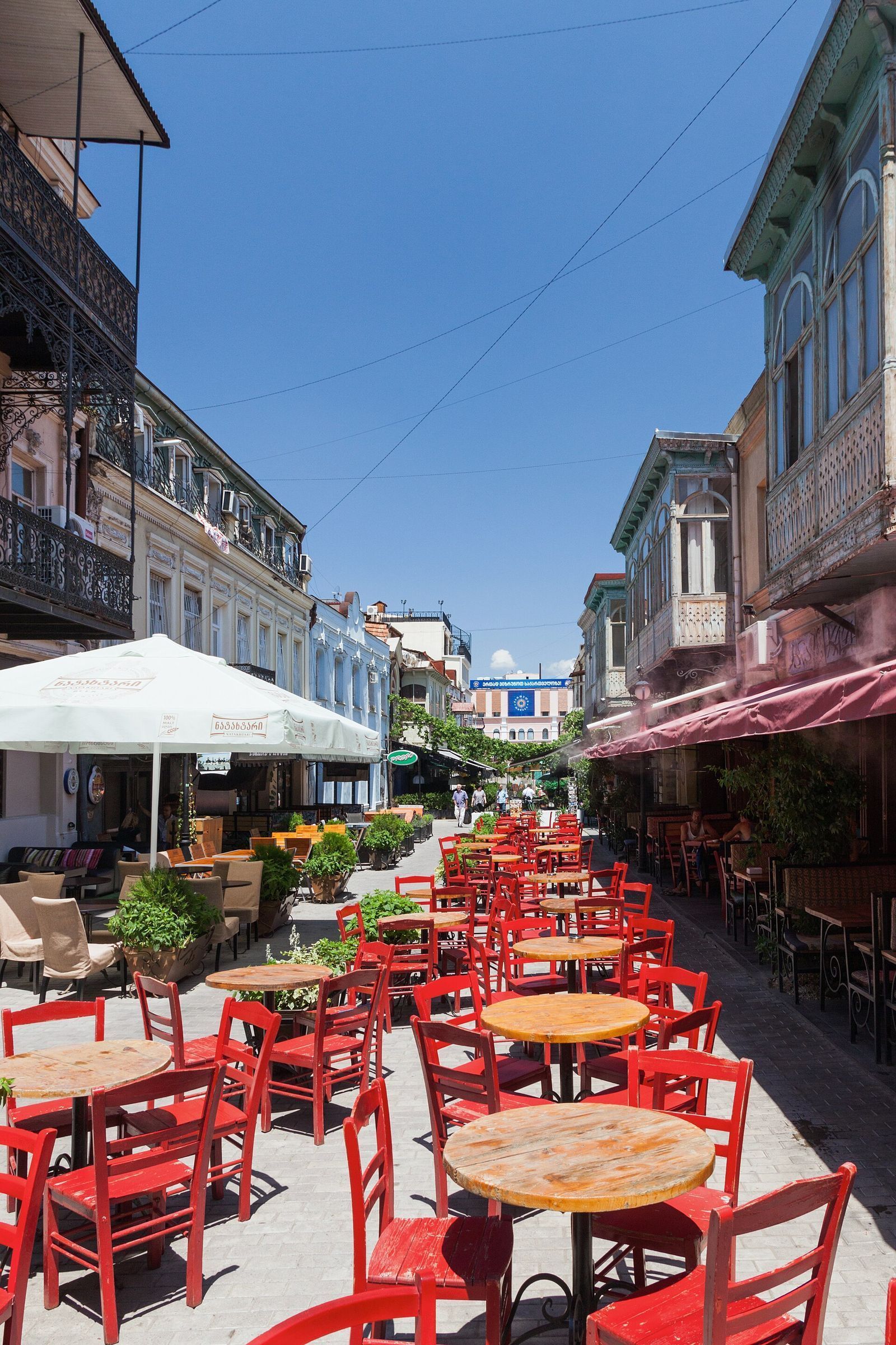 Rows of red chairs and outdoor cafe tables down the middle of pedestrian Erekle II Street in Kala