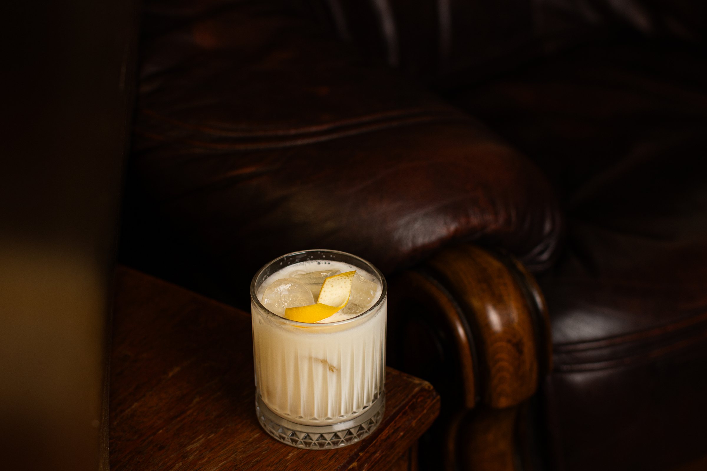 A pale creamy cocktail on ice with a lemon twist at Crossroads Bar