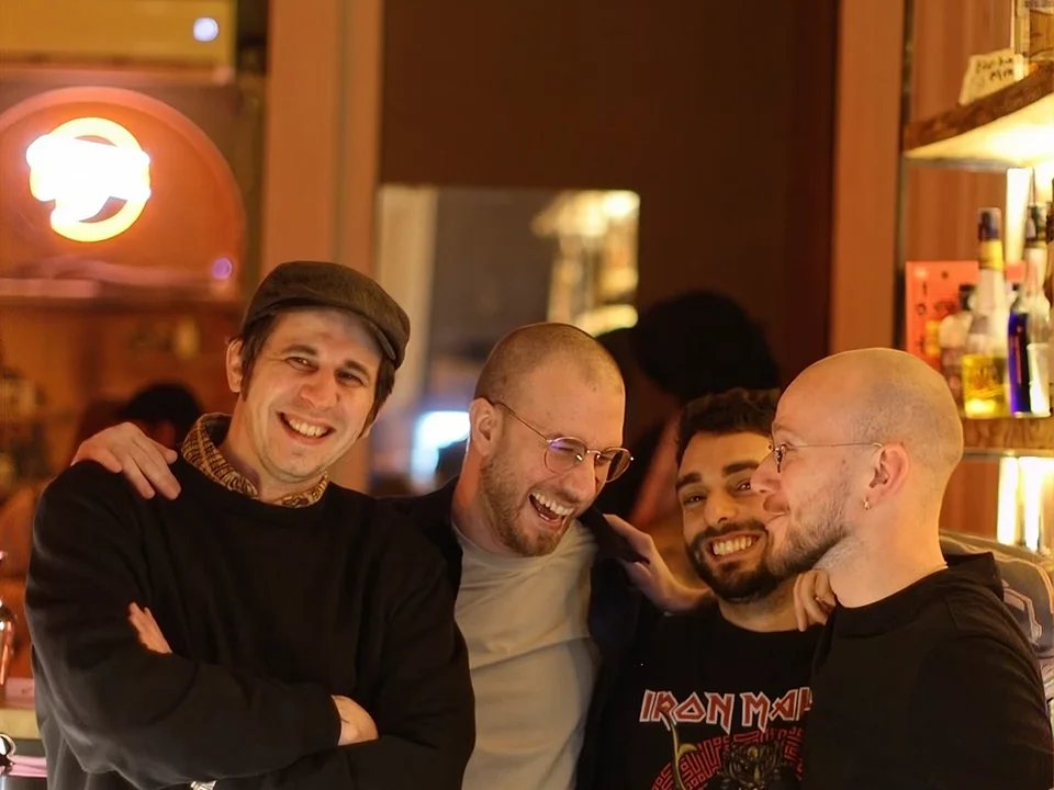 Four friends laughing together at the bar of Crossroads Bar in Sololaki