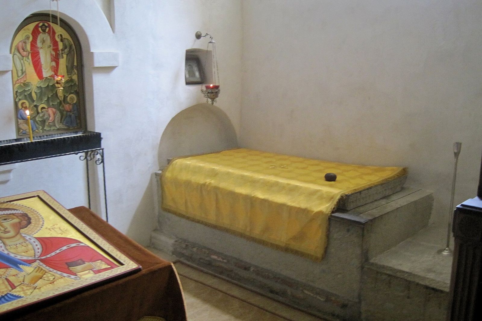 A tomb draped in yellow cloth with the Jerusalem stone on top, inside the Church of the Transfiguration, the cave church at Lavra Monastery