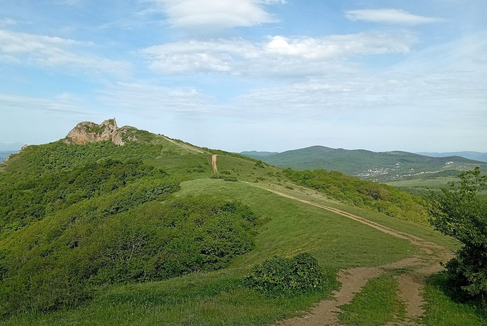 Kojori Fortress on the rocky top of Mount Azeula, with a dirt track running along the green ridge toward it