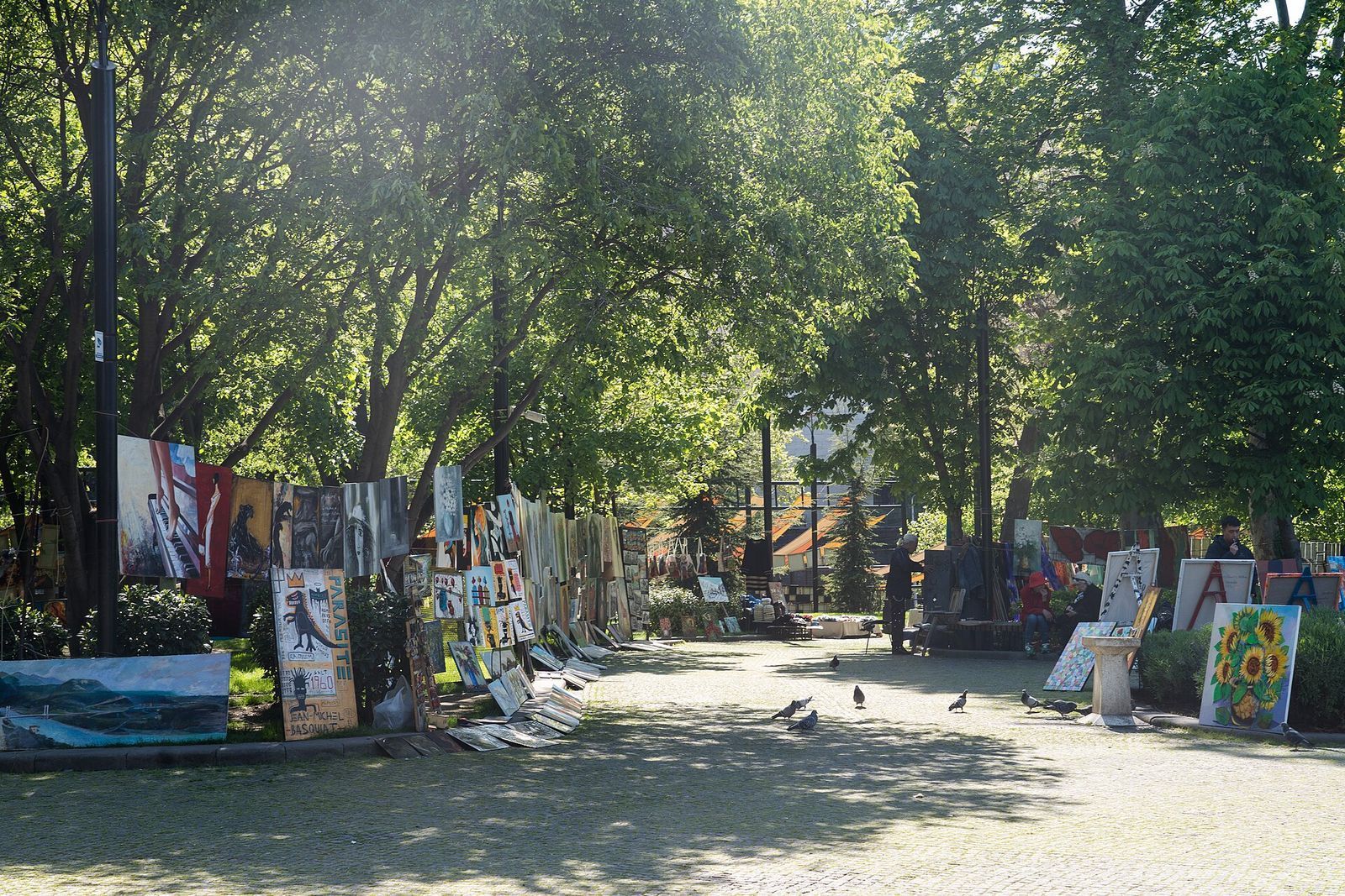 Paintings for sale propped against the trees and lampposts of 9 March Park at the Dry Bridge painters' market