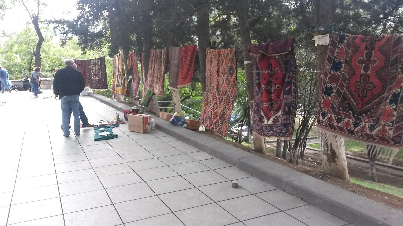 Kilims and rugs hung along a walkway in 9 March Park at the Dry Bridge Market