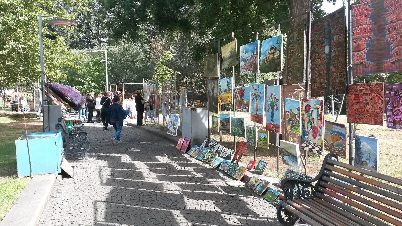 Landscapes, flower still lifes and Old Tbilisi scenes hung on stands along a path in 9 March Park