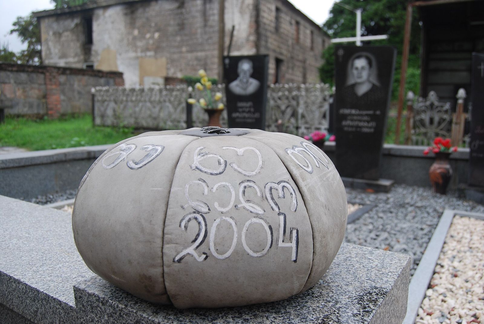 A stitched leather lelo burti ball marked 2004, resting on a grave in the village cemetery at Shukhuti