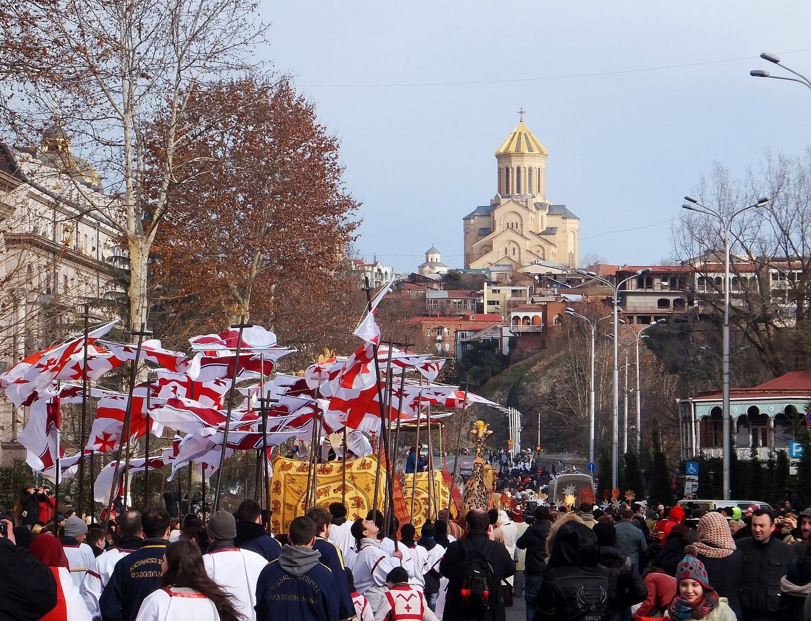 The Alilo procession on 7 January, with Georgian flags and a gold float moving through Tbilisi, Sameba Cathedral on the hill behind