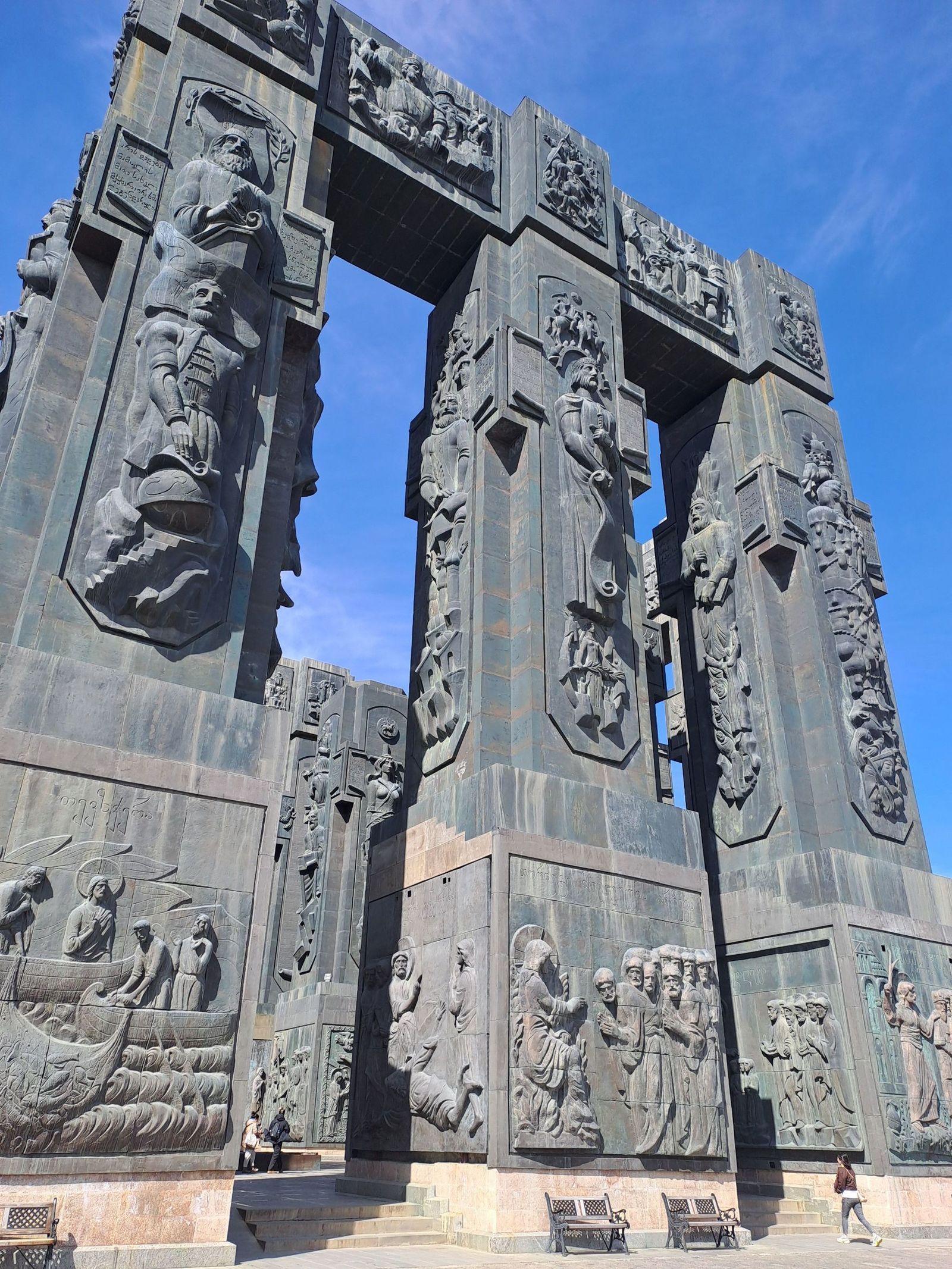 The giant carved stone pillars of the Chronicles of Georgia monument in Tbilisi against a blue sky
