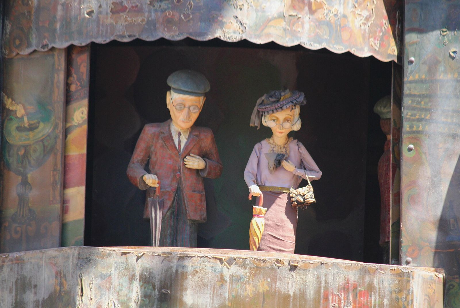 The elderly couple puppets, a man in glasses and a woman with an umbrella, on the clock tower stage late in the show