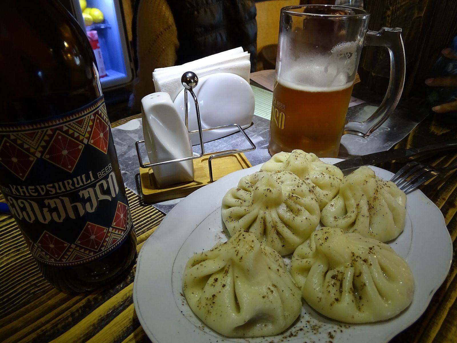 A plate of khinkali with a mug of beer and a bottle of Khevsuruli beer in a pub in Kazbegi