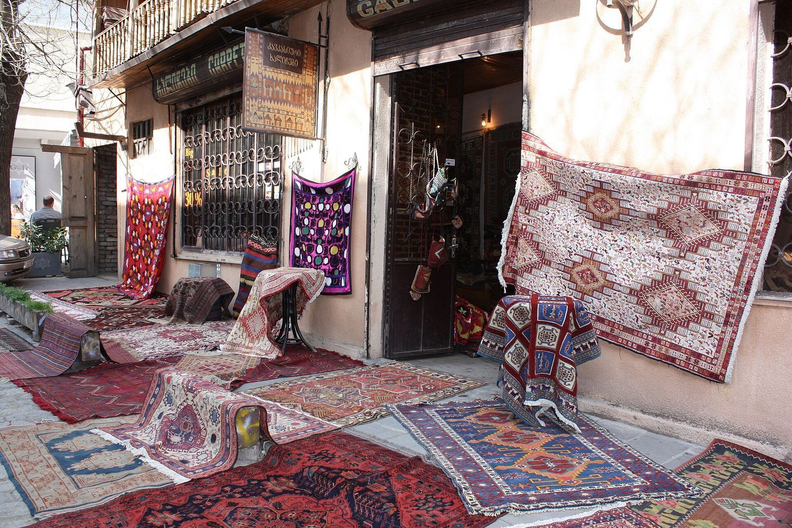 Kilims and rugs hung on the walls and spread on the pavement outside Caucasian Carpets Gallery on Erekle II Street