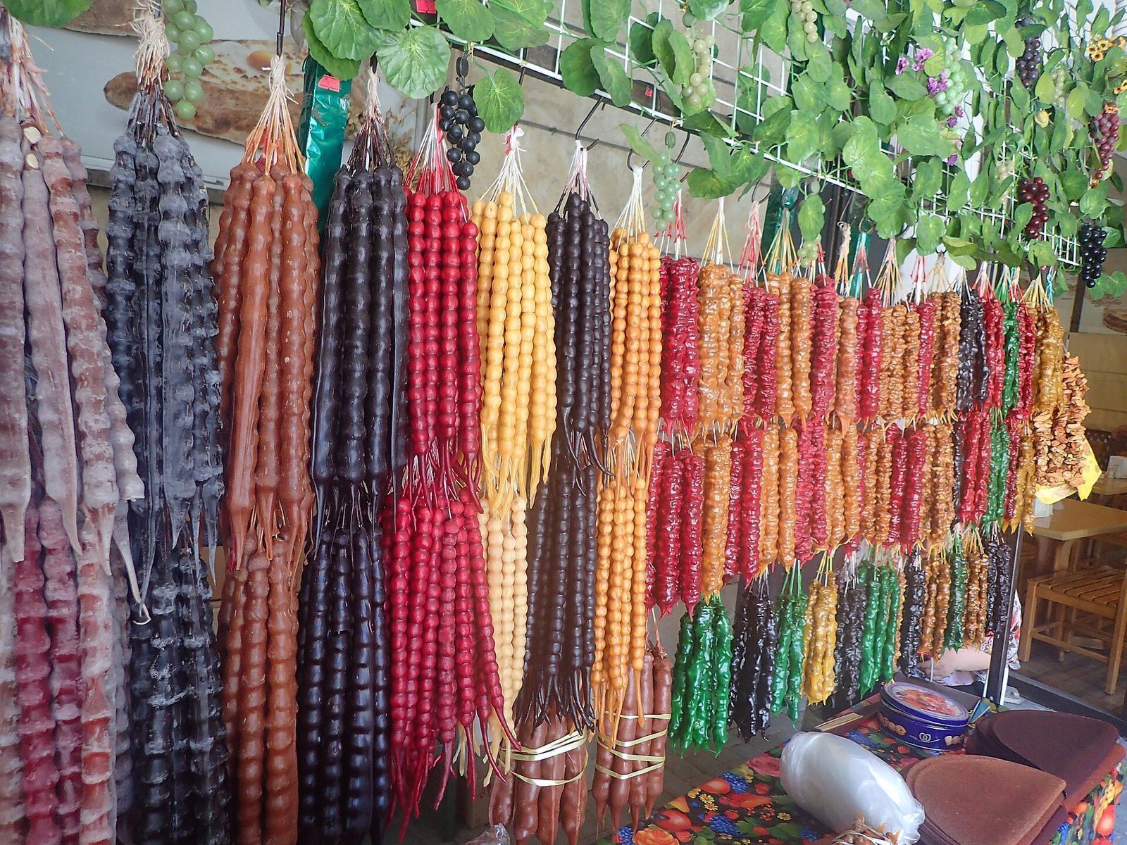 Strings of churchkhela in red, black, yellow, orange and green hanging at a sweet stall in Georgia