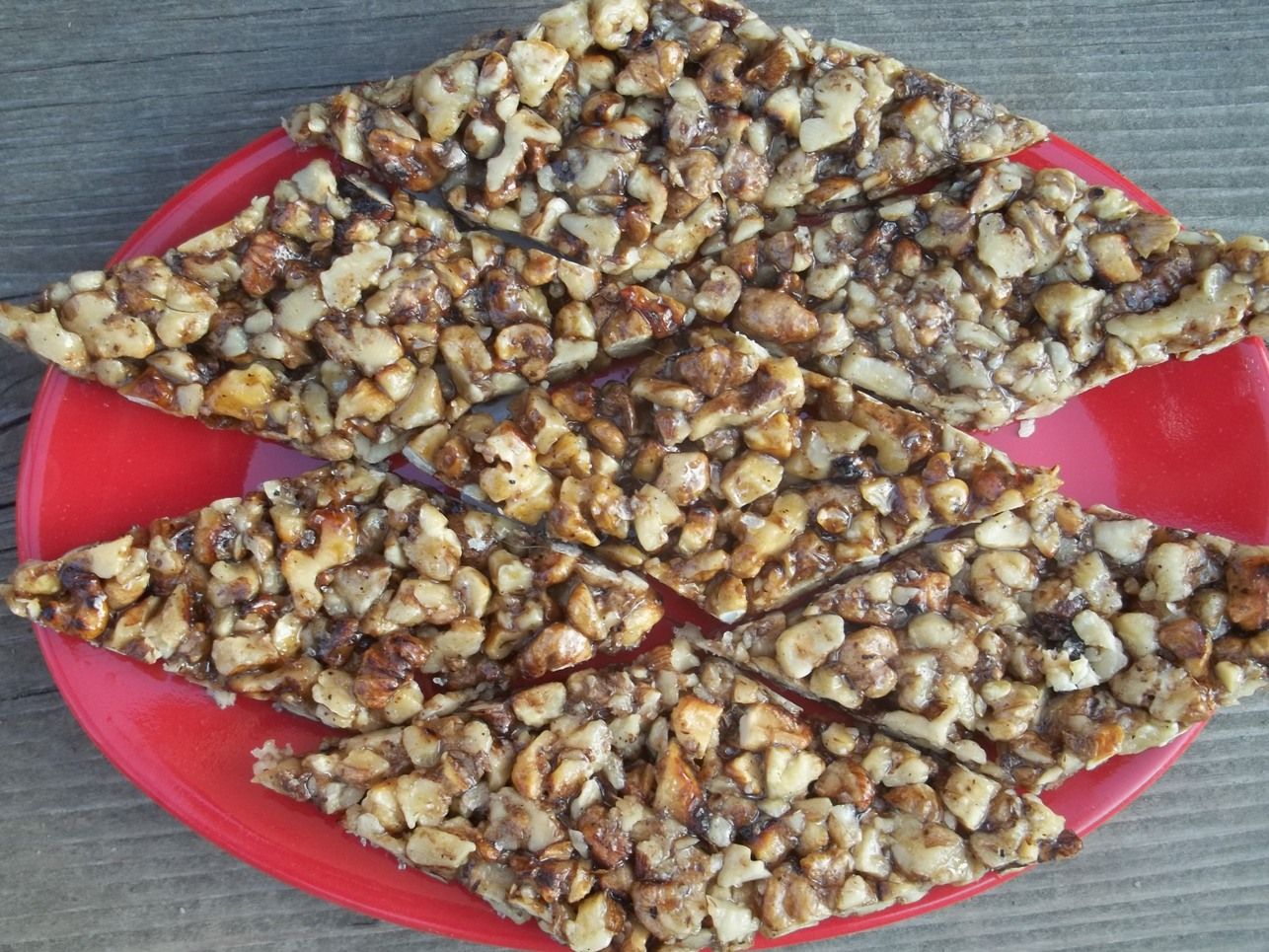 Diamonds of gozinaki, toasted walnuts set in caramelized honey, on a red plate