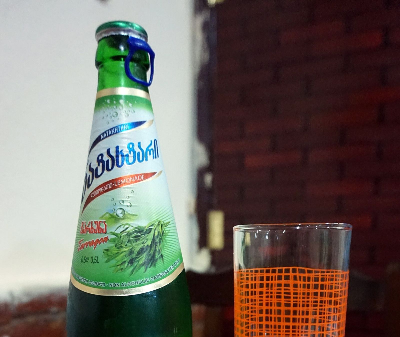 A bottle of Natakhtari tarkhuna, the Georgian tarragon lemonade, next to a glass