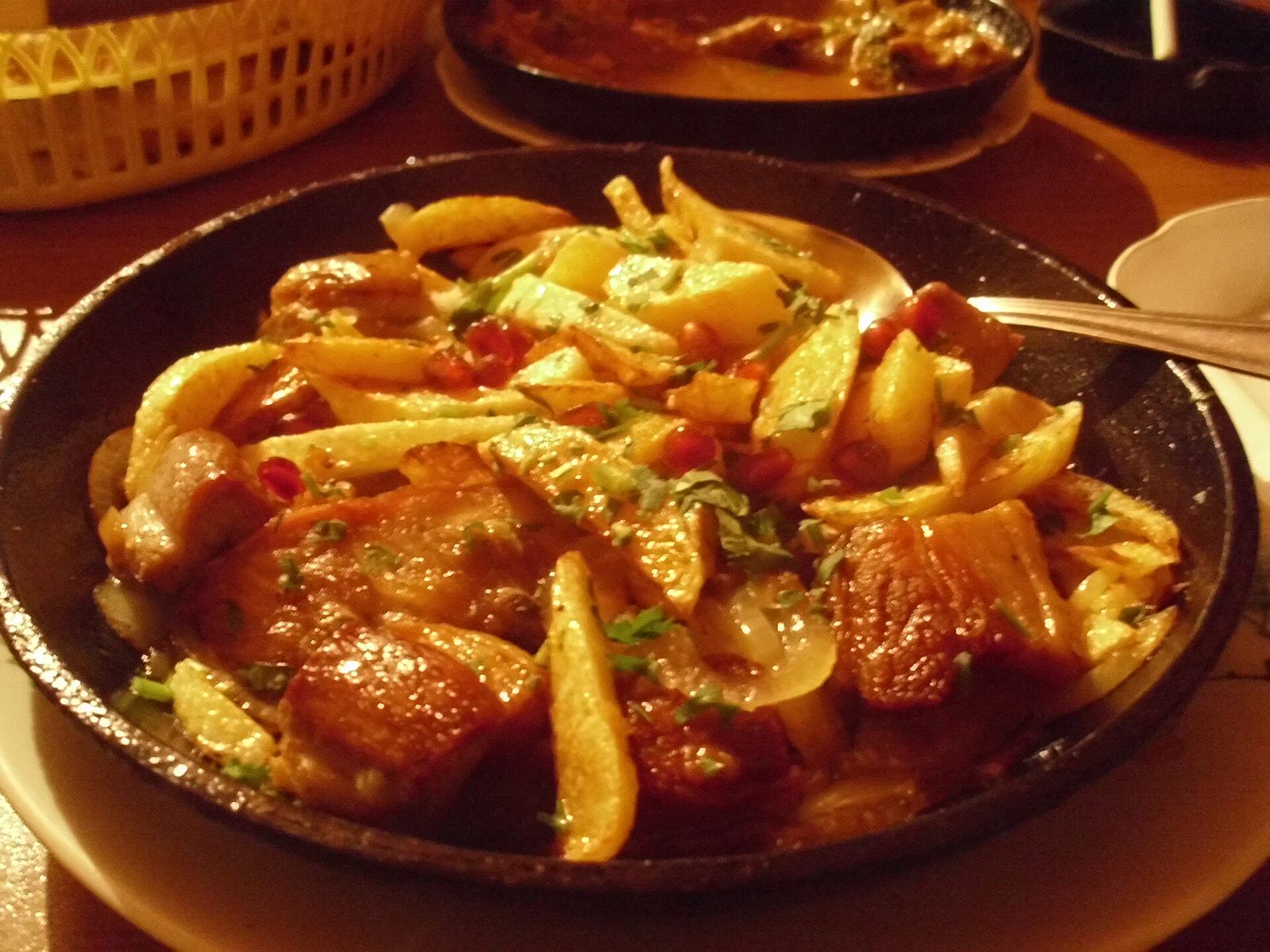 Ojakhuri, fried pork and potatoes with onion and herbs, in a black pan