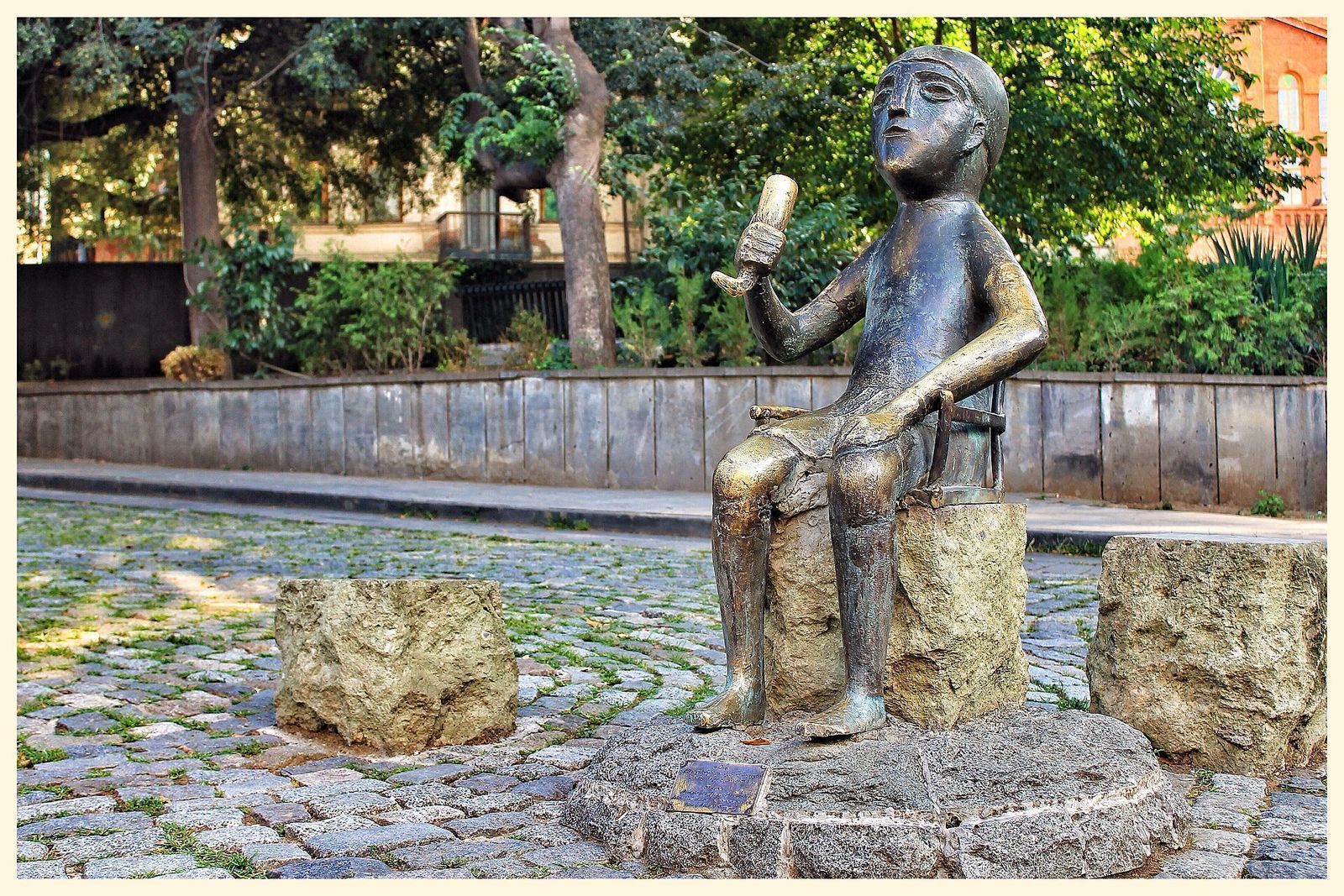 The bronze tamada statue in Tbilisi, a seated figure raising a drinking horn on a cobbled square