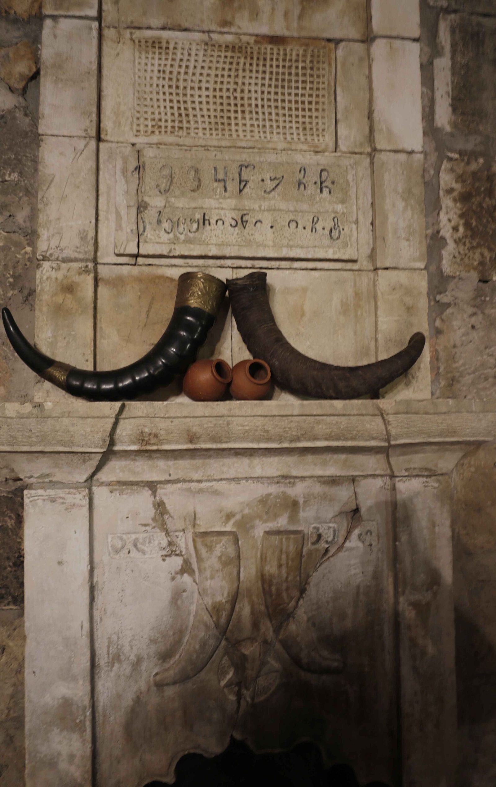 A pair of kantsi, Georgian drinking horns, on a stone mantel with two small clay cups