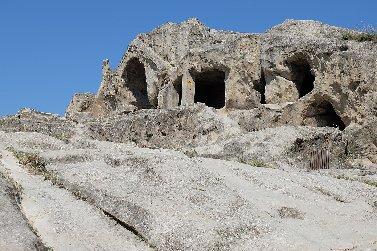 Rock-cut halls and doorways carved into the pale stone ridge of the Uplistsikhe cave town near Gori