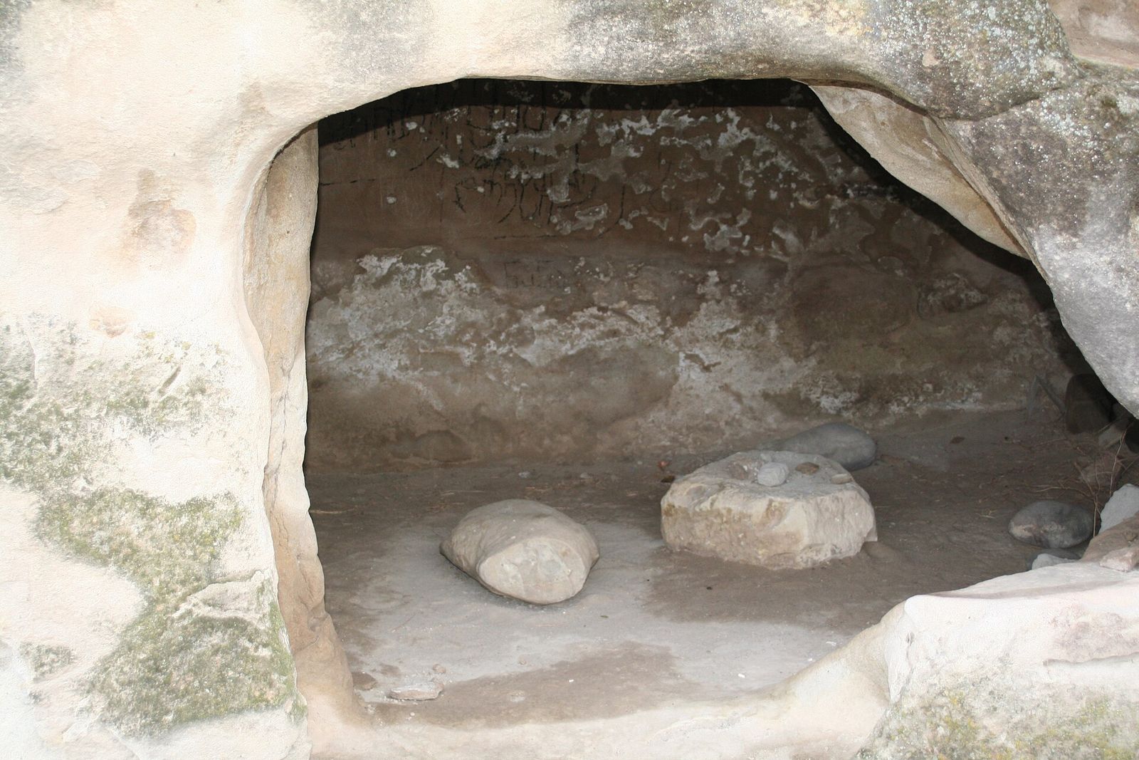 A small rock-cut room at Uplistsikhe, a plain chamber dug into the sandstone with a few loose stones on its floor