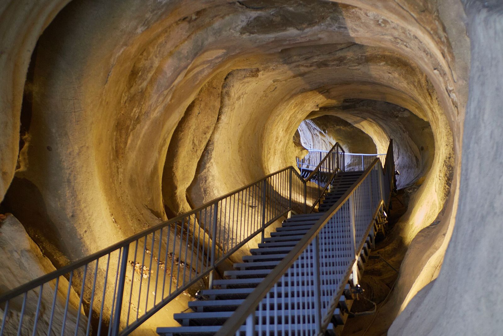A metal staircase running down through the rock-cut tunnel at Uplistsikhe