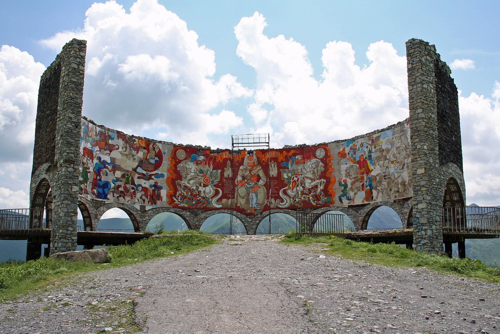 The curved Russia-Georgia Friendship Monument near Gudauri, its tiled mural framed by two stone towers