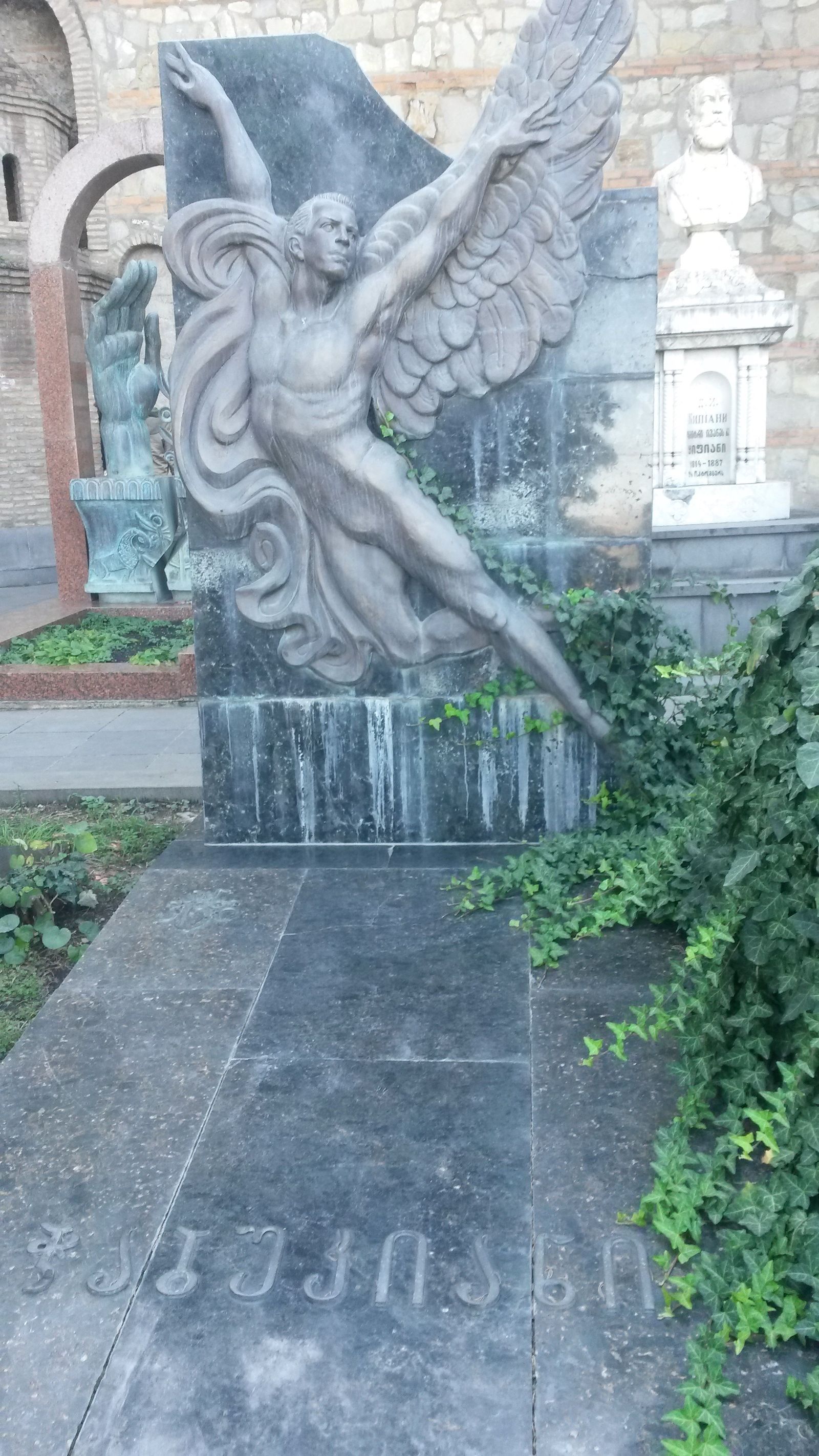 Vakhtang Chabukiani's gravestone at the Mtatsminda Pantheon, a carved winged dancer leaping across a dark stone slab