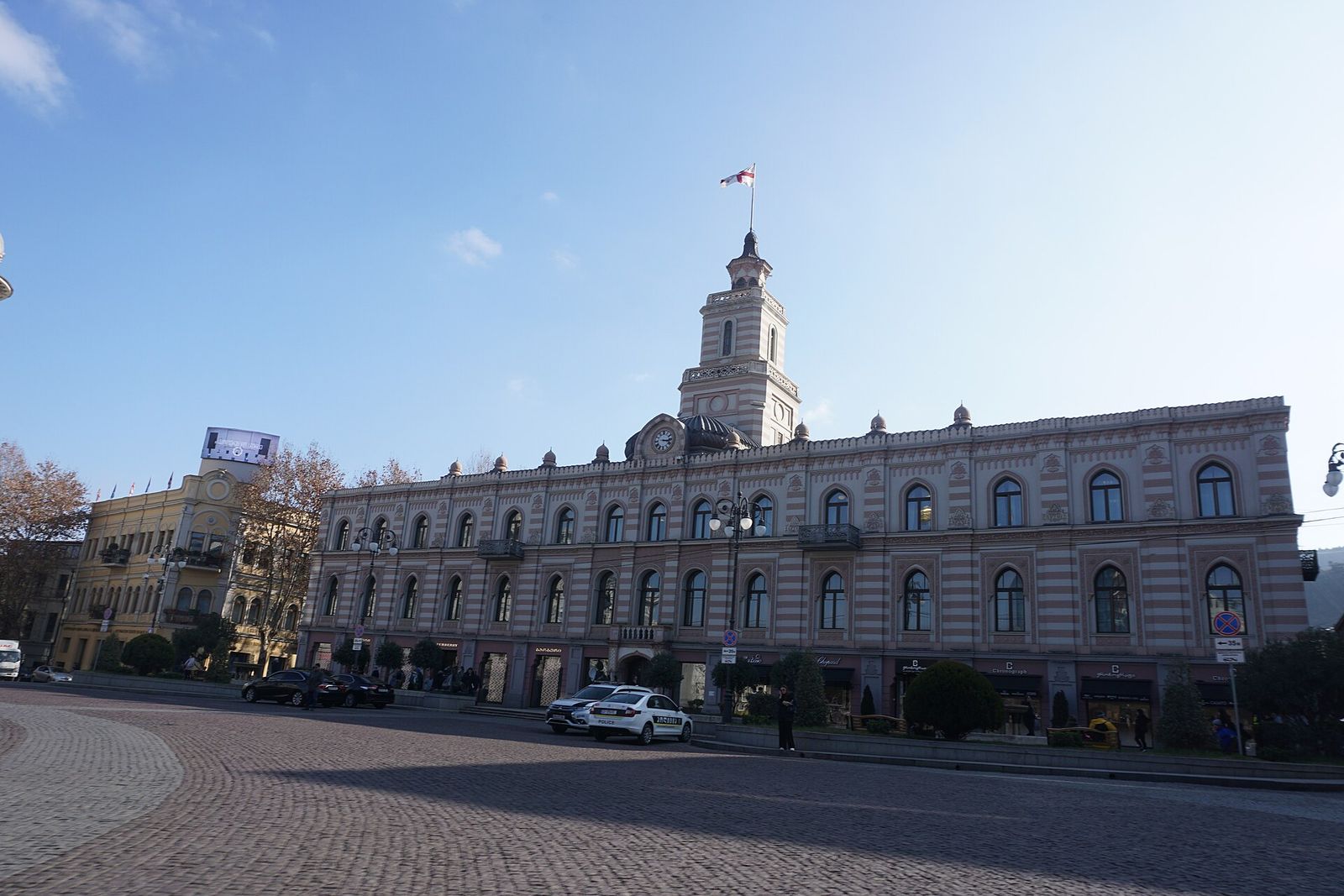 The Old City Hall on Freedom Square in Tbilisi, with its clock tower and flag, where most free walking tours meet