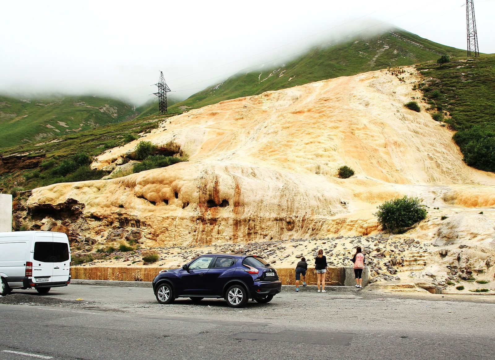 Orange and cream mineral terraces spilling down the hillside beside the road near the Jvari Pass