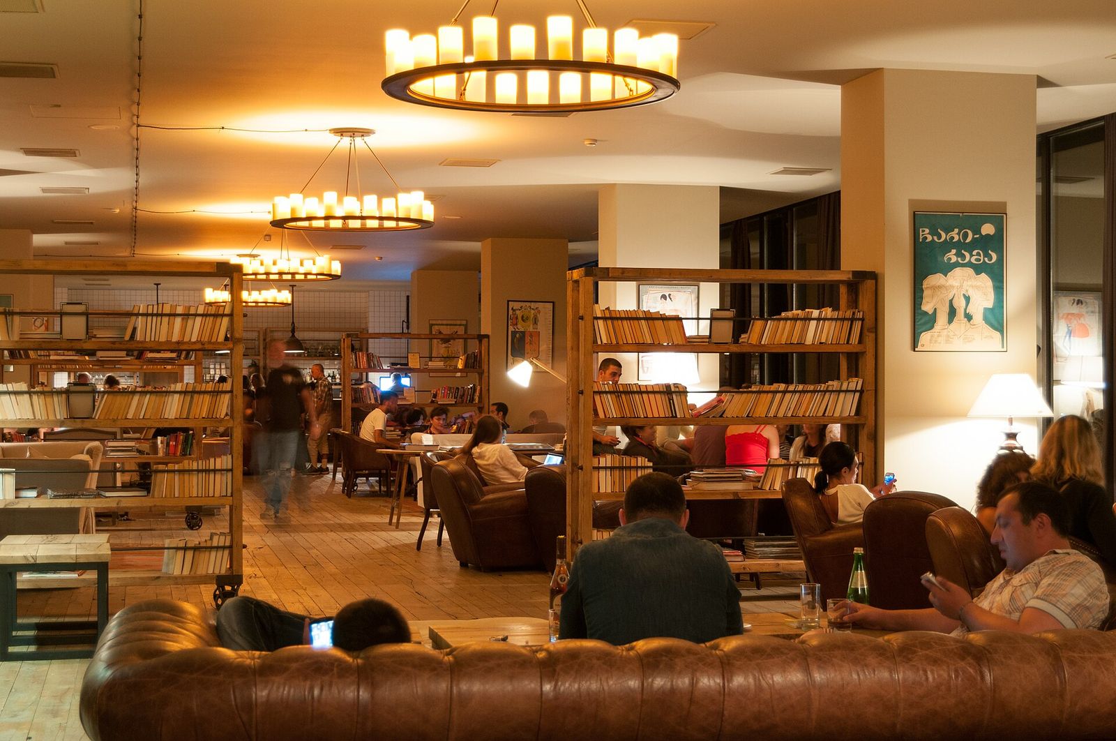 The lobby lounge of Rooms Hotel Kazbegi, with bookshelves, candle chandeliers and leather sofas