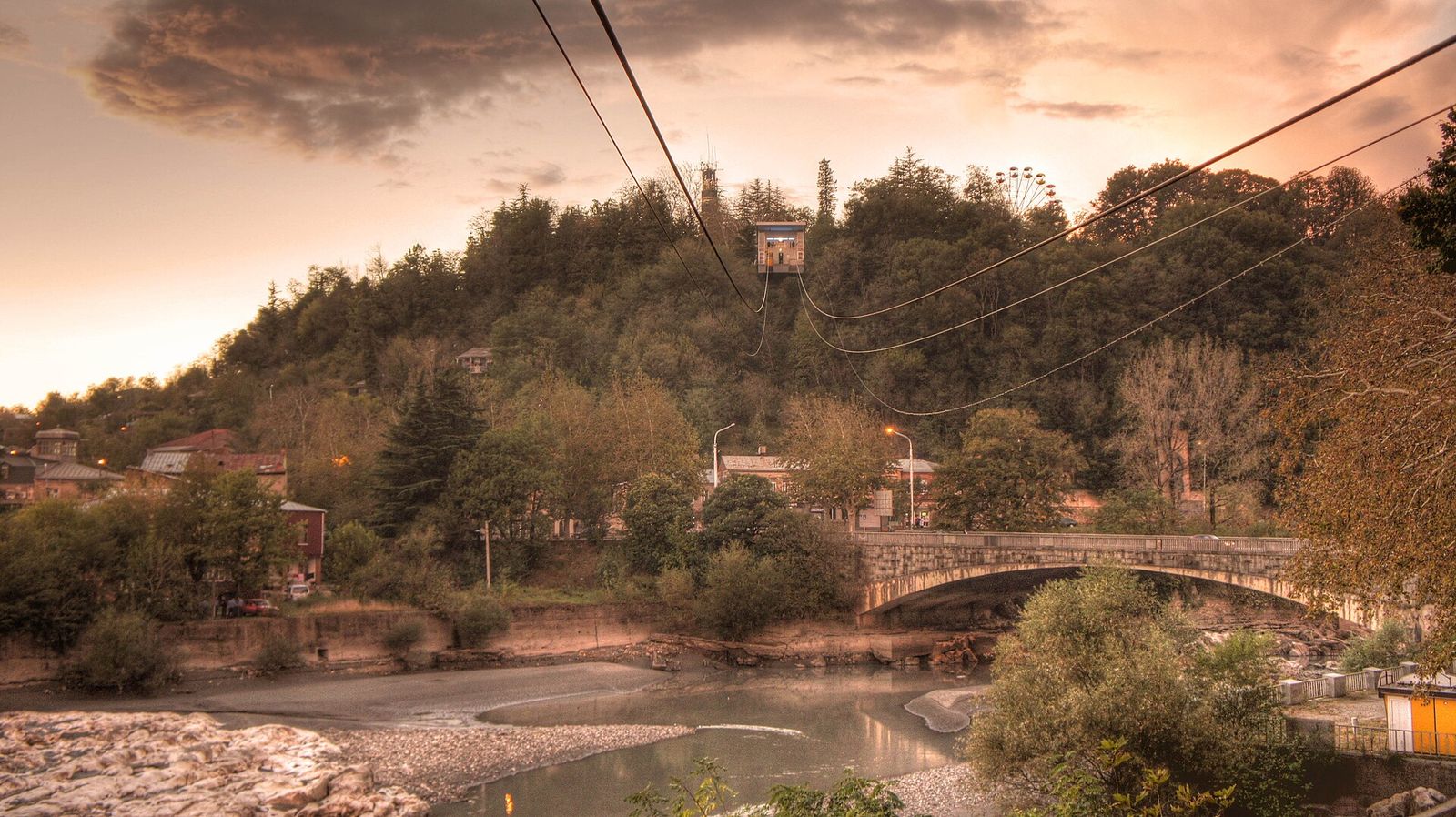 A Kutaisi cable car cabin on its way up the wooded hill above the Rioni, with the Ferris wheel at the top