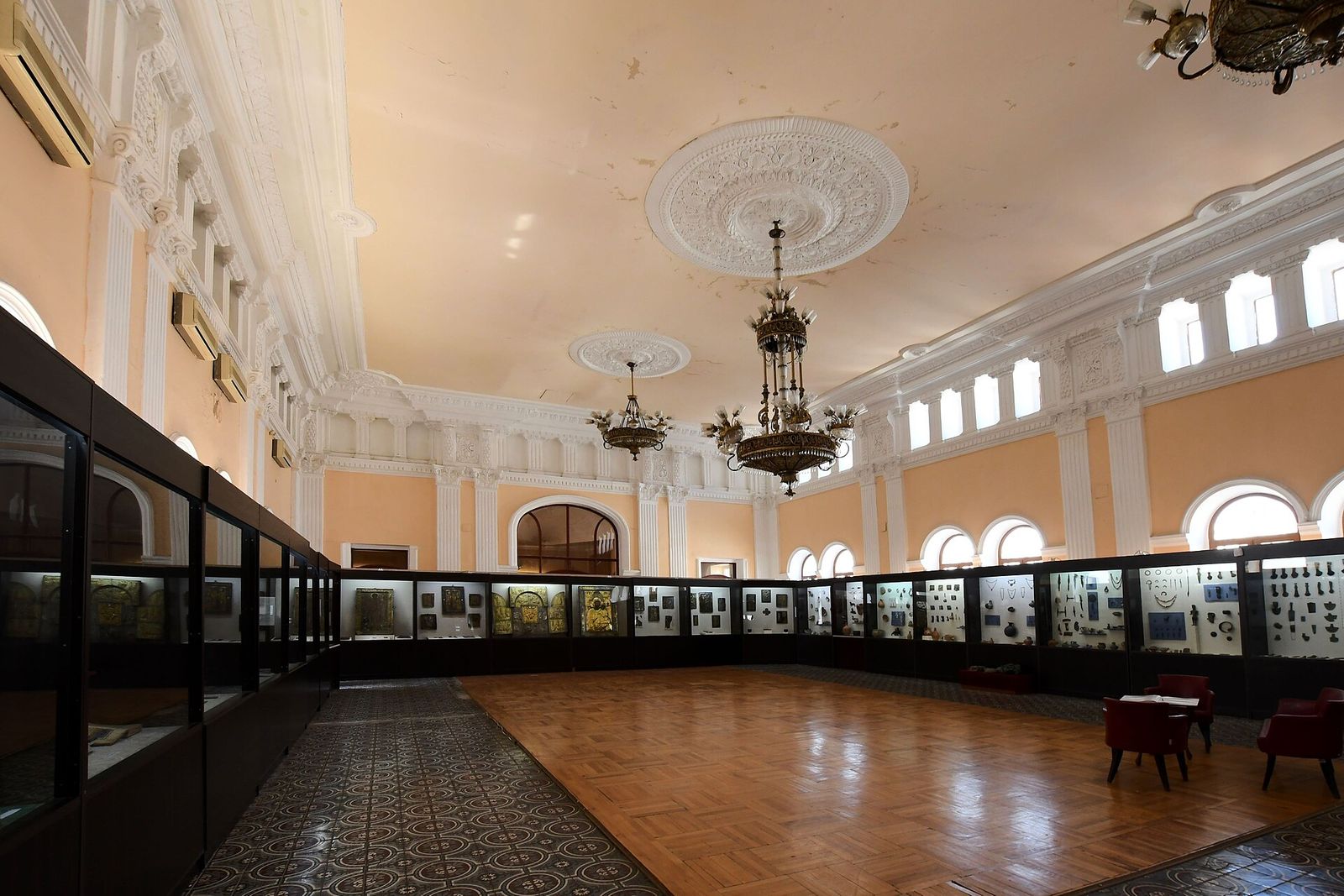 An exhibition hall of the Kutaisi State Historical Museum, with display cases along the walls under chandeliers