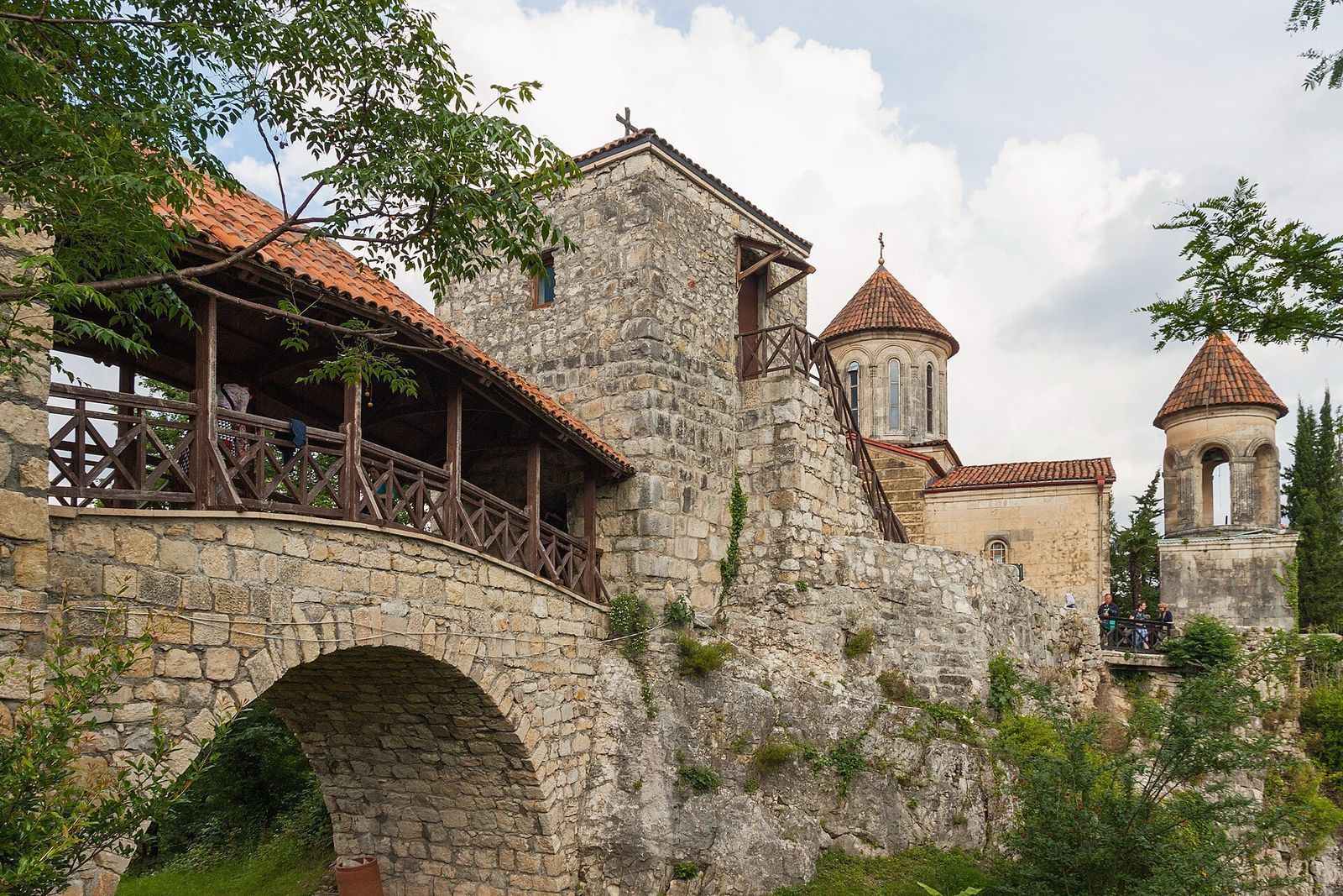 Motsameta Monastery on its cliff, reached by an arched stone footbridge with a wooden gallery